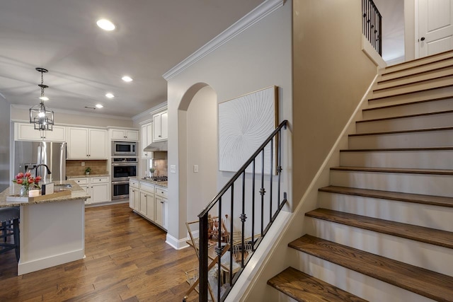 kitchen with a kitchen island with sink, light stone countertops, white cabinets, and appliances with stainless steel finishes