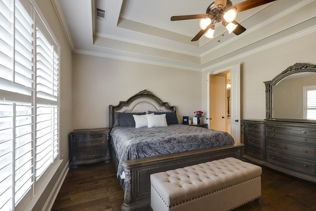 bedroom featuring dark wood-type flooring, ornamental molding, and a raised ceiling