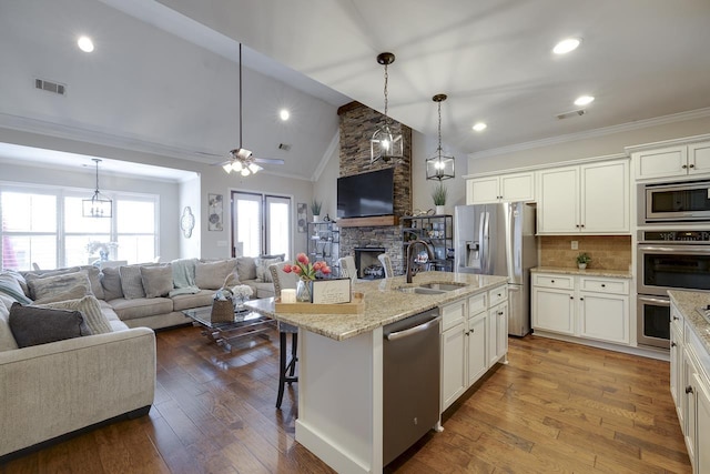 kitchen featuring stainless steel appliances, decorative light fixtures, sink, and a center island with sink