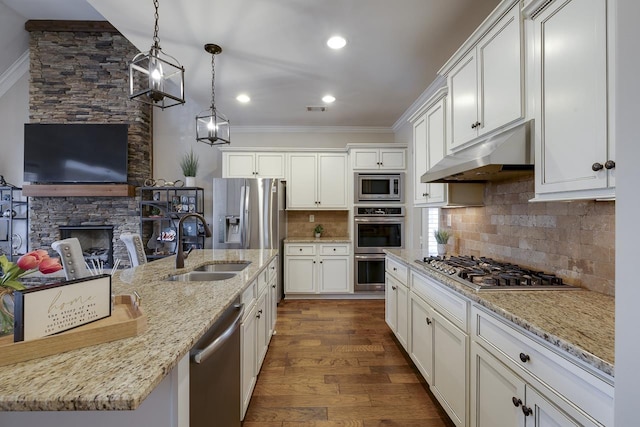 kitchen with appliances with stainless steel finishes, white cabinetry, sink, hanging light fixtures, and light stone countertops