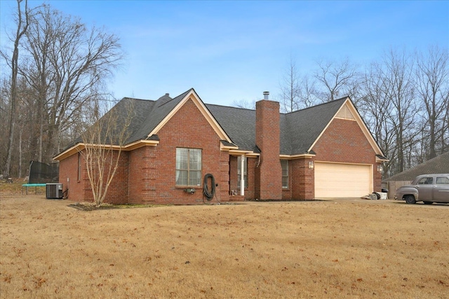 view of front of house featuring central AC, a garage, a trampoline, and a front yard