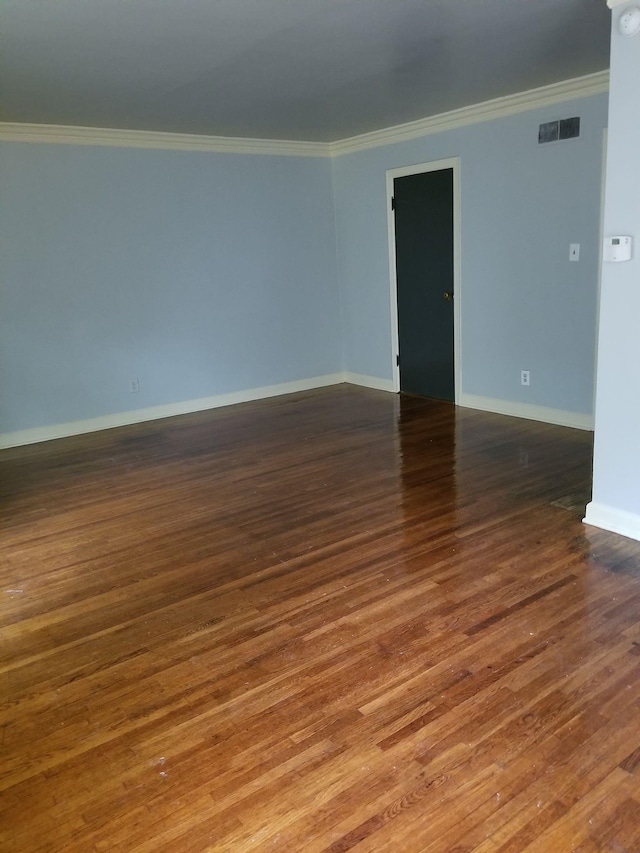 empty room featuring ornamental molding and dark hardwood / wood-style flooring