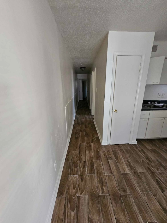 hall featuring sink, a textured ceiling, and dark hardwood / wood-style flooring