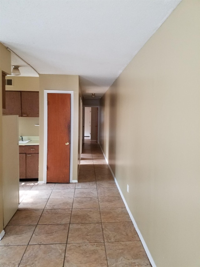 corridor featuring sink and light tile patterned floors