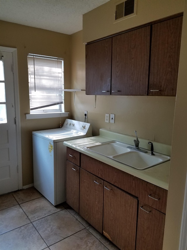 laundry room featuring washer / dryer, sink, cabinets, light tile patterned floors, and a textured ceiling