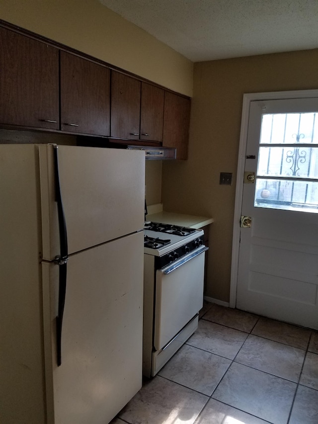 kitchen featuring white appliances, extractor fan, dark brown cabinets, and light tile patterned floors