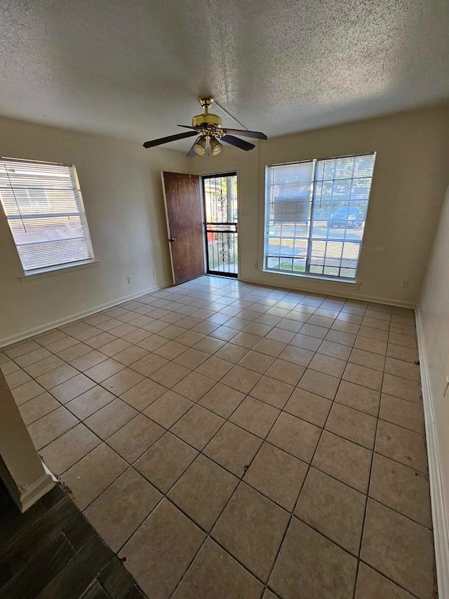 spare room featuring ceiling fan, a textured ceiling, and light tile patterned floors