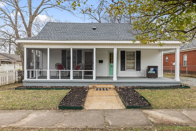 view of front of property with covered porch, a sunroom, and a front yard