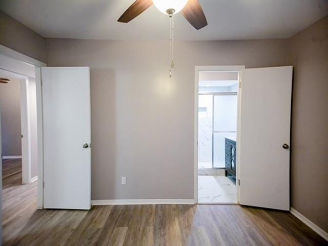 unfurnished bedroom featuring wood-type flooring, ceiling fan, and ensuite bathroom