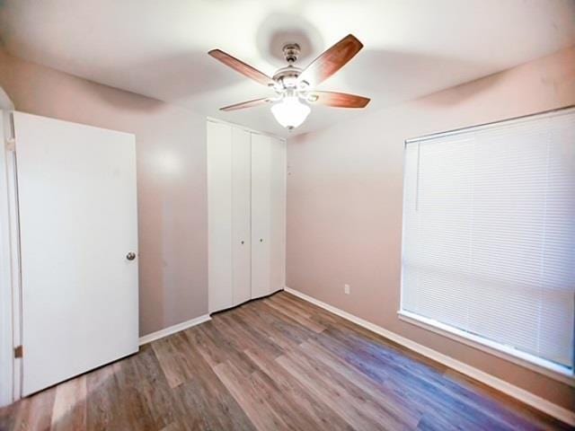 unfurnished bedroom featuring hardwood / wood-style floors, ceiling fan, and a closet