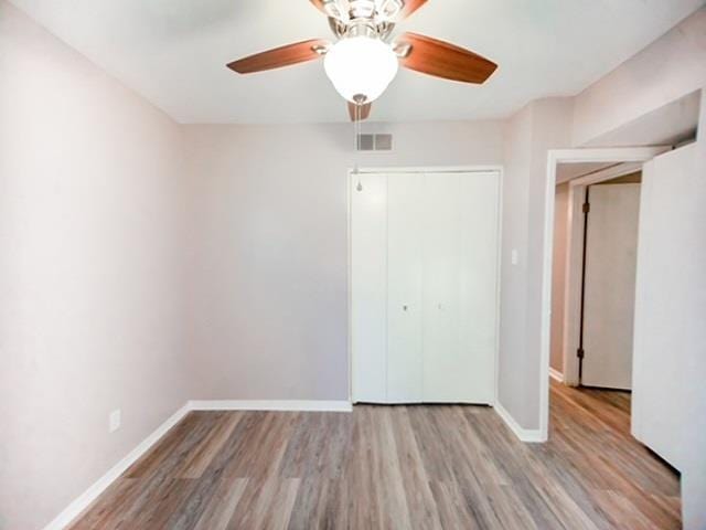 unfurnished bedroom with ceiling fan, light wood-type flooring, and a closet