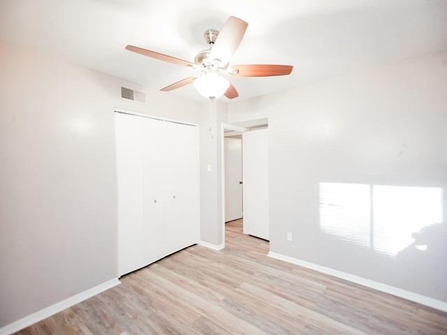 unfurnished bedroom with ceiling fan, a closet, and light wood-type flooring