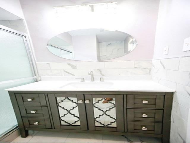 bathroom featuring vanity, tile walls, and walk in shower