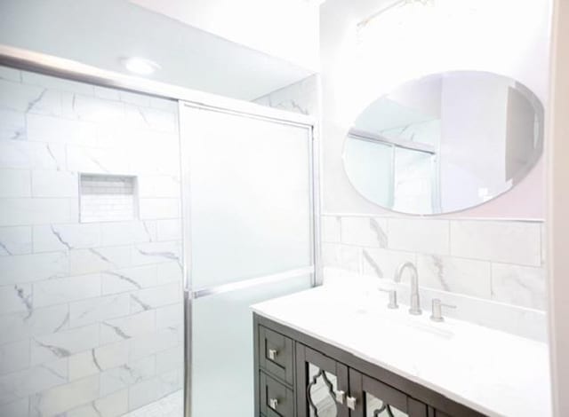 bathroom featuring vanity, an enclosed shower, tile walls, and backsplash