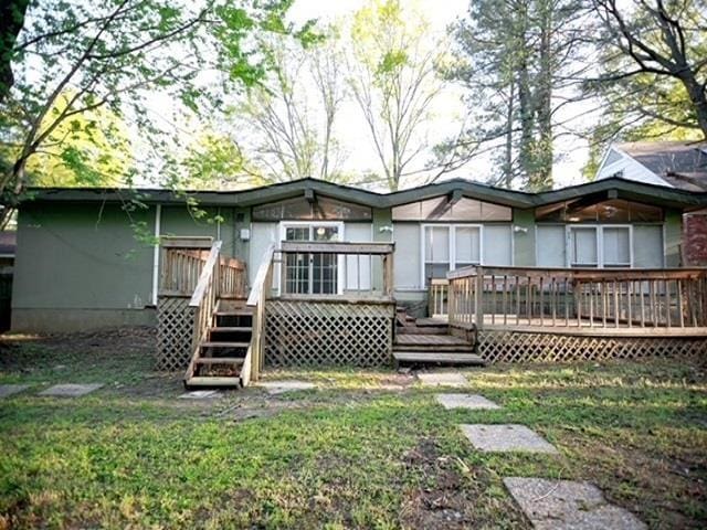 rear view of property with a wooden deck and a lawn