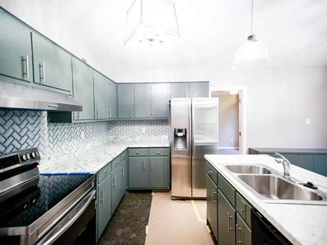 kitchen with tasteful backsplash, sink, gray cabinetry, hanging light fixtures, and stainless steel appliances