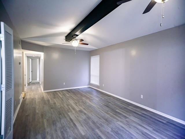 spare room featuring ceiling fan, dark hardwood / wood-style floors, and lofted ceiling with beams