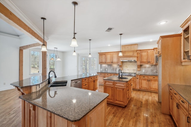 kitchen featuring pendant lighting, sink, dishwasher, decorative backsplash, and a large island with sink