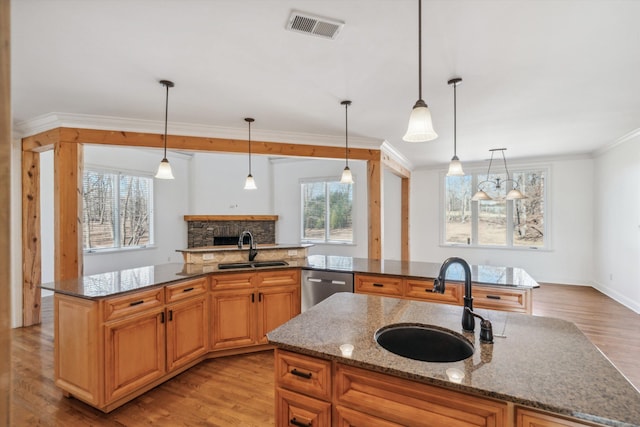 kitchen featuring pendant lighting, stainless steel dishwasher, sink, and dark stone countertops