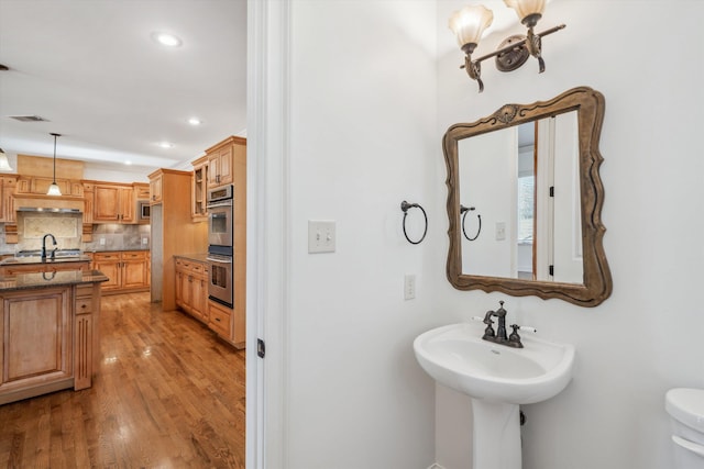 bathroom featuring tasteful backsplash, hardwood / wood-style floors, and sink