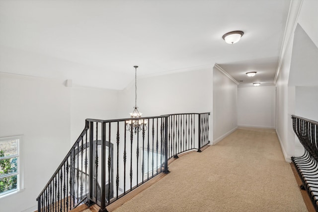 hallway featuring crown molding, a chandelier, and light carpet