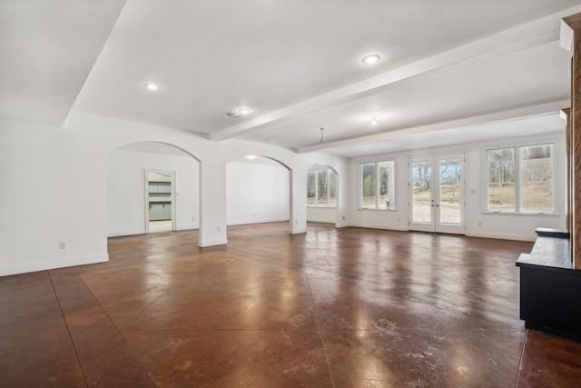 unfurnished living room featuring beamed ceiling and french doors