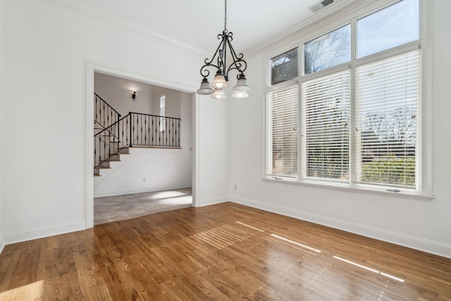 unfurnished dining area with an inviting chandelier, crown molding, and hardwood / wood-style flooring