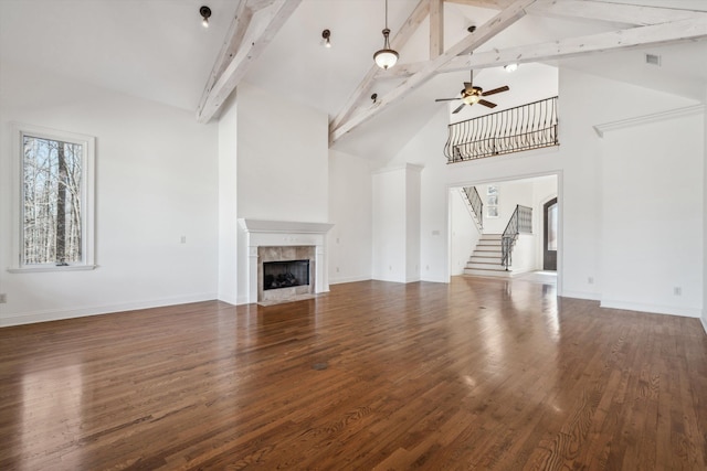 unfurnished living room featuring a tile fireplace, ceiling fan, beam ceiling, high vaulted ceiling, and dark hardwood / wood-style floors