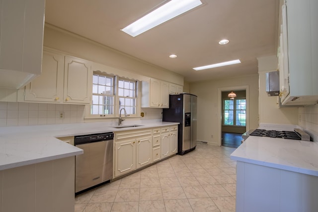 kitchen featuring sink, tasteful backsplash, stainless steel appliances, light stone countertops, and white cabinets