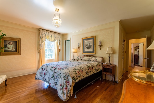 bedroom with ornamental molding and dark wood-type flooring