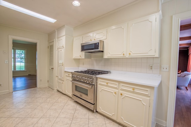 kitchen with ornamental molding, appliances with stainless steel finishes, white cabinets, and decorative backsplash