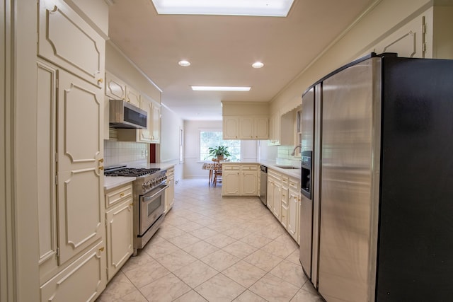 kitchen featuring tasteful backsplash, sink, light tile patterned floors, stainless steel appliances, and cream cabinets