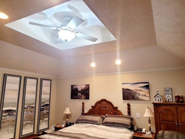 bedroom featuring ceiling fan, a tray ceiling, and a textured ceiling