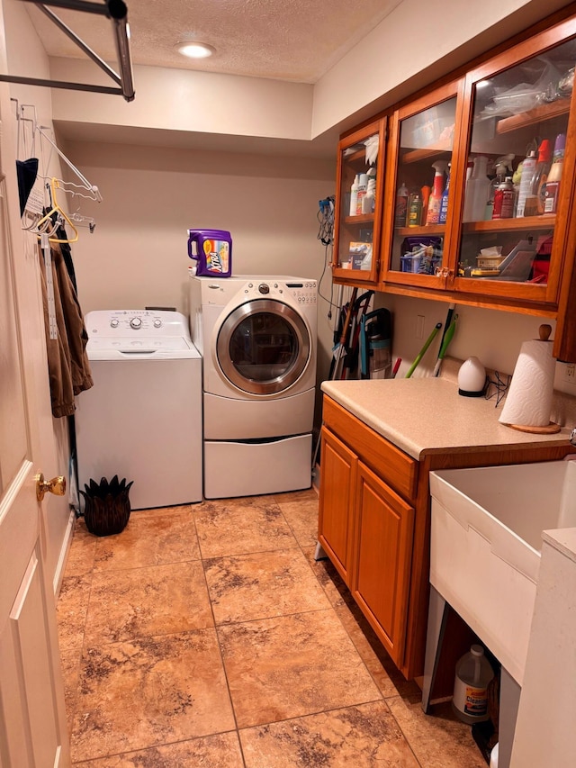 clothes washing area with independent washer and dryer, cabinets, and a textured ceiling