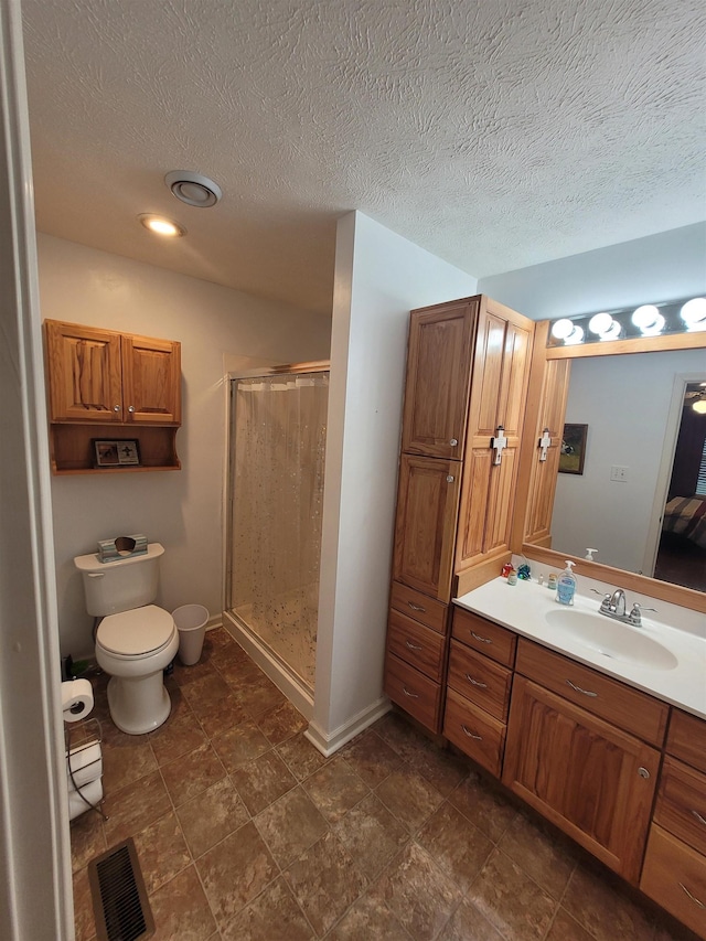 bathroom featuring vanity, a textured ceiling, toilet, and walk in shower