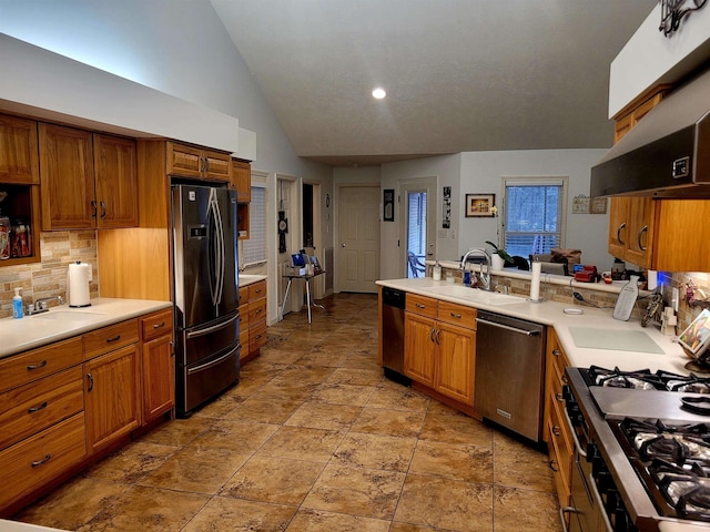 kitchen with vaulted ceiling, range hood, sink, kitchen peninsula, and stainless steel appliances