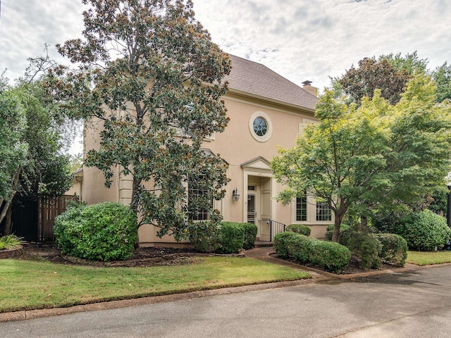 view of front of property with a front lawn, a chimney, and stucco siding