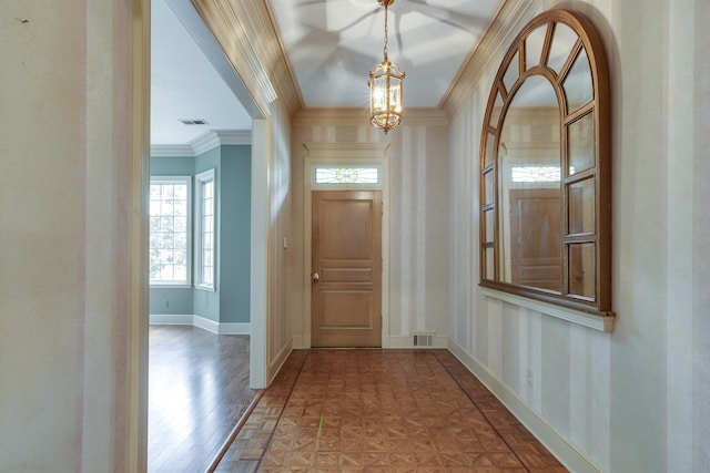 foyer entrance featuring an inviting chandelier, baseboards, visible vents, and ornamental molding