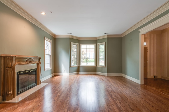 unfurnished living room with a premium fireplace, wood finished floors, visible vents, baseboards, and ornamental molding