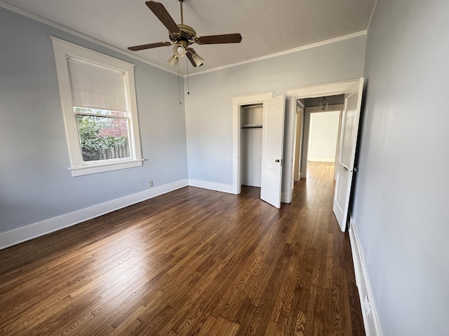 unfurnished bedroom featuring ceiling fan, ornamental molding, dark hardwood / wood-style floors, and a closet