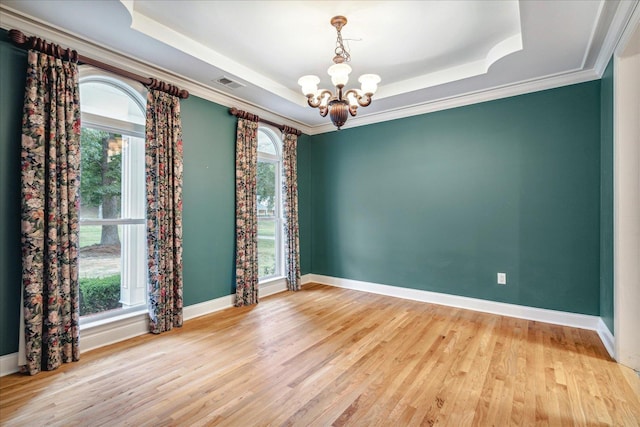 unfurnished room featuring ornamental molding, a tray ceiling, light hardwood / wood-style floors, and a notable chandelier