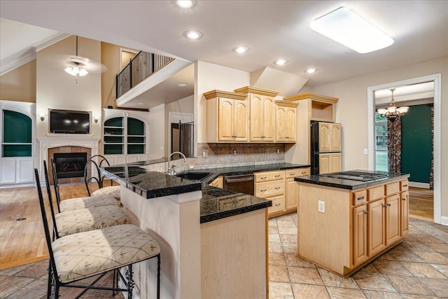 kitchen with a tile fireplace, a kitchen island, high end refrigerator, kitchen peninsula, and light brown cabinets