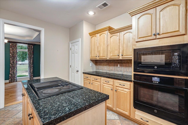 kitchen with light brown cabinetry, tasteful backsplash, black appliances, and a center island