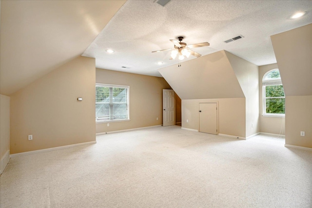 bonus room featuring vaulted ceiling, light carpet, ceiling fan, and a textured ceiling