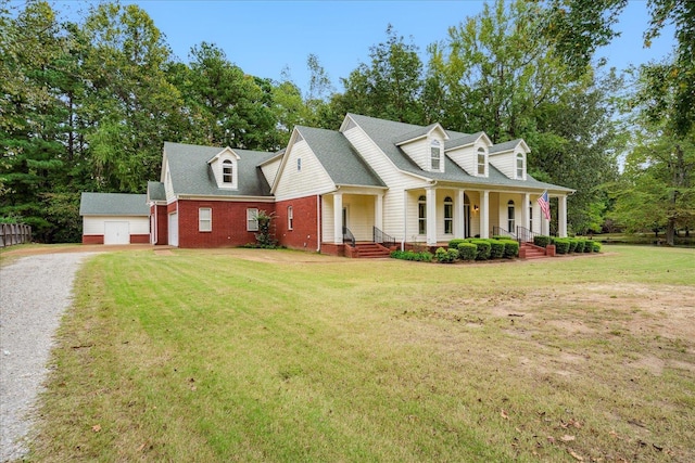 new england style home with an outbuilding, a garage, a front yard, and covered porch