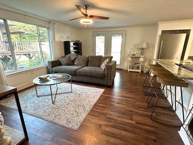 living room with crown molding, dark wood-type flooring, ceiling fan, and french doors