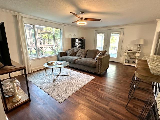 living room featuring crown molding, dark wood-type flooring, a textured ceiling, and french doors