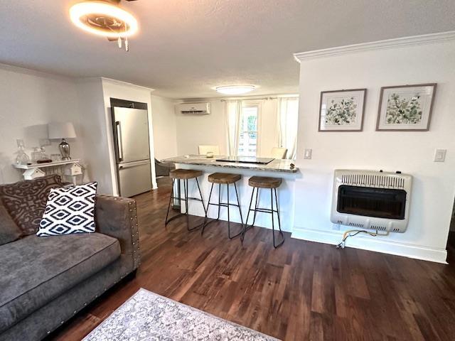 living room featuring ornamental molding, dark hardwood / wood-style floors, heating unit, and a wall mounted AC