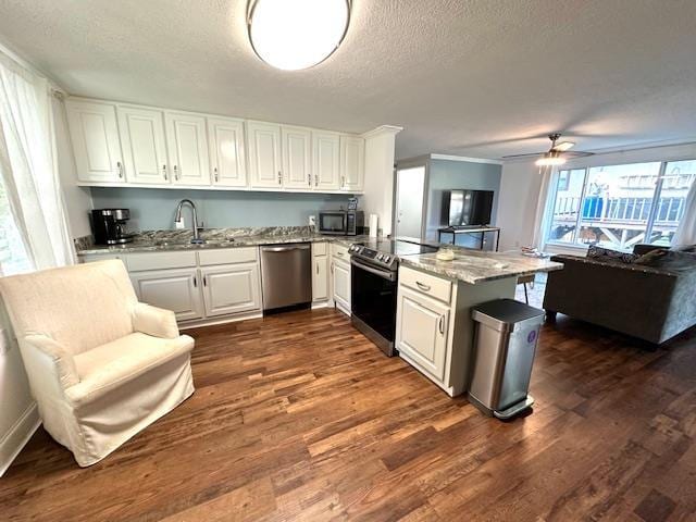 kitchen with appliances with stainless steel finishes, white cabinets, dark hardwood / wood-style flooring, light stone counters, and kitchen peninsula