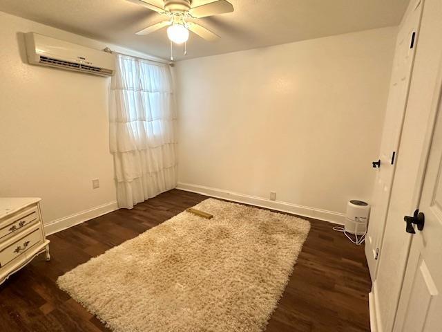 spare room featuring ceiling fan, dark hardwood / wood-style flooring, and a wall unit AC